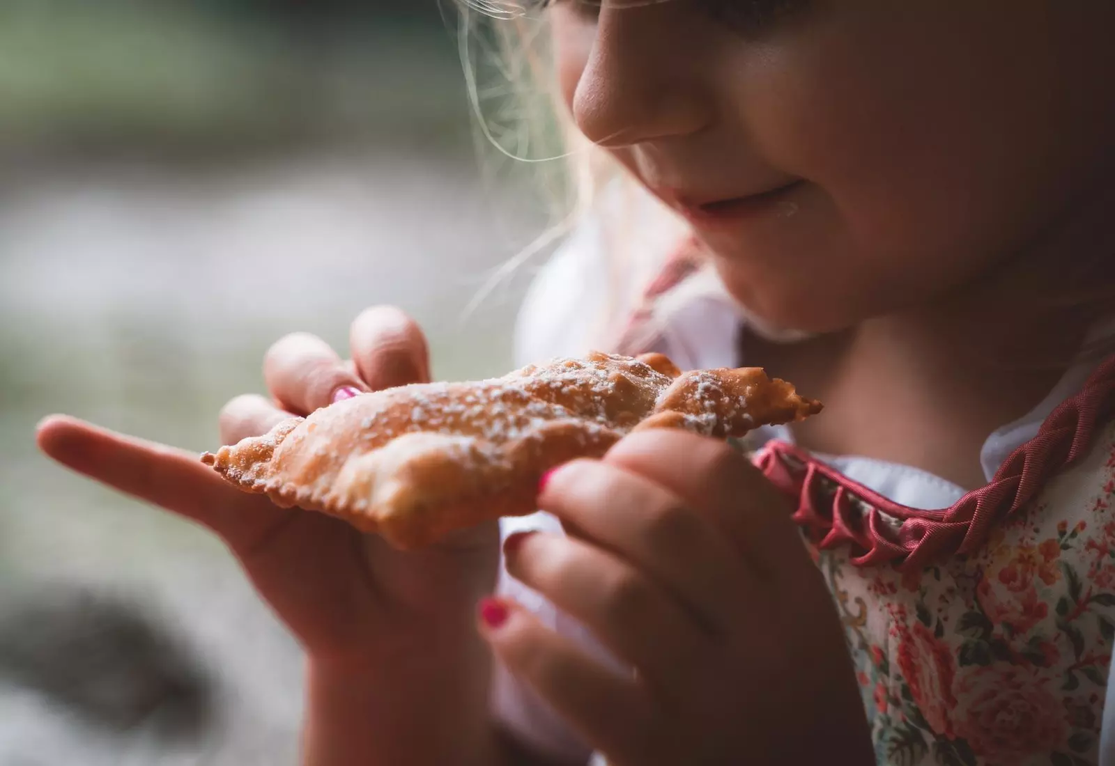Lächelndes Mädchen isst einen Südtiroler Krapfen